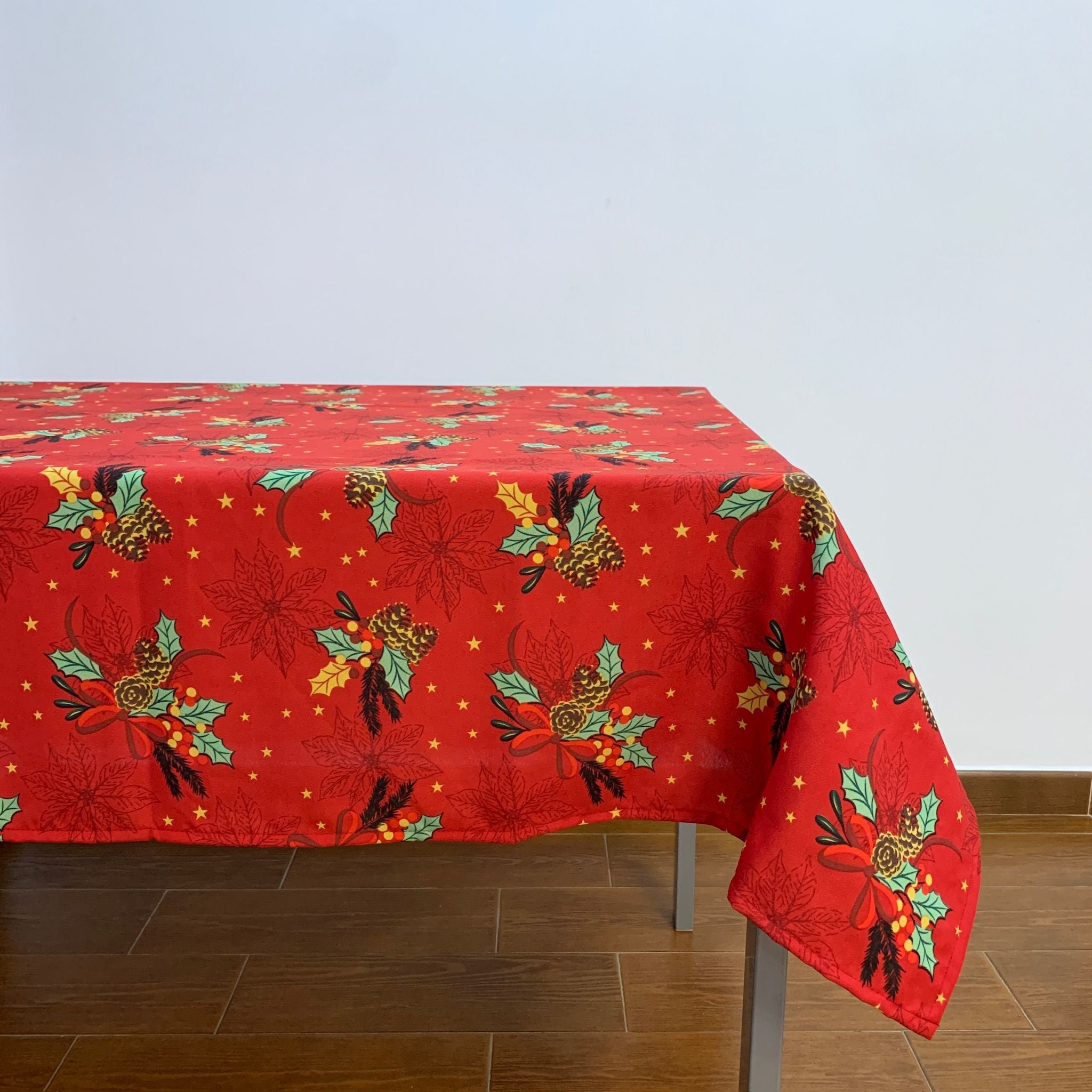 A toalha de mesa Natal Azevinho Anti-Nódoas é composta por um vermelho vivo e é coberta delicadamente por um arranjo de azevinhos e pinhas de Natal. Num tom mais claro e muito subtilmente, econtram-se igualmente dispersos nesta toalha a forma da flor de natal e umas estrelinhas pequenas e douradas.